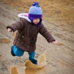 Addie jumping in mud puddles at Appleton Farms in Ipswich, MA