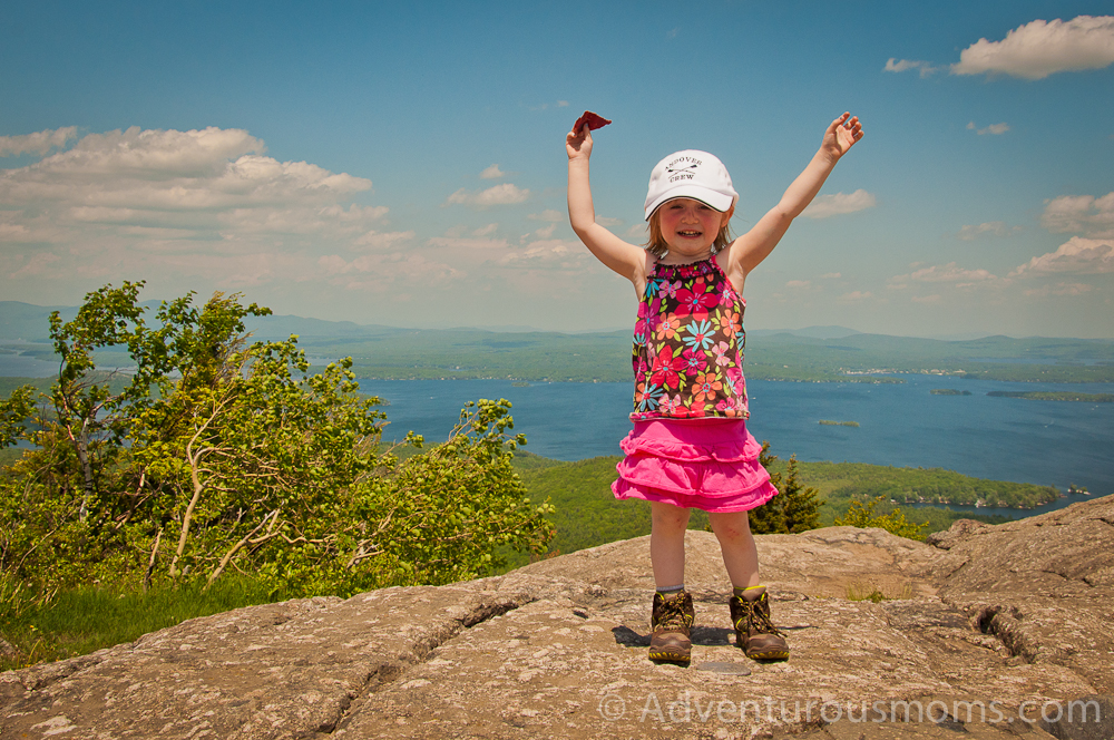 Addie standing on the summit marker of Mt. Major in Alton, NH